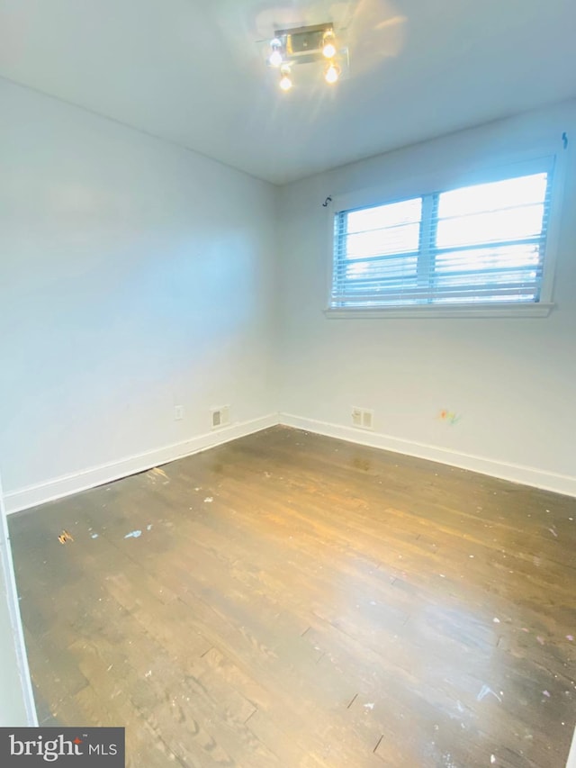 spare room with baseboards and wood finished floors