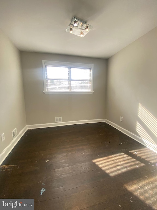 unfurnished room featuring visible vents, baseboards, and hardwood / wood-style flooring