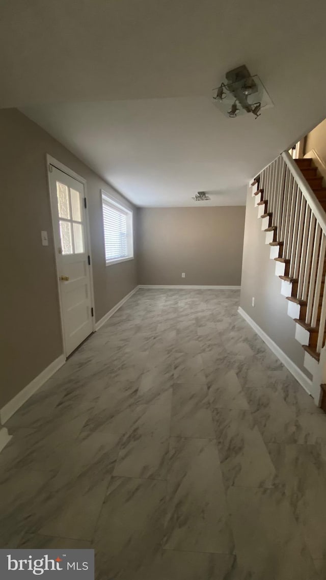 foyer featuring stairs, marble finish floor, and baseboards