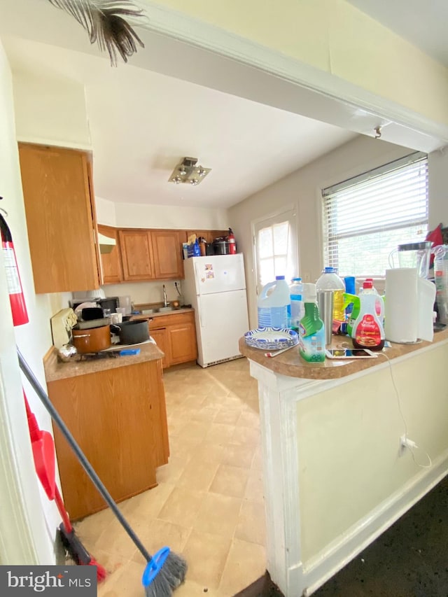 kitchen featuring range hood, white refrigerator, and light tile patterned floors