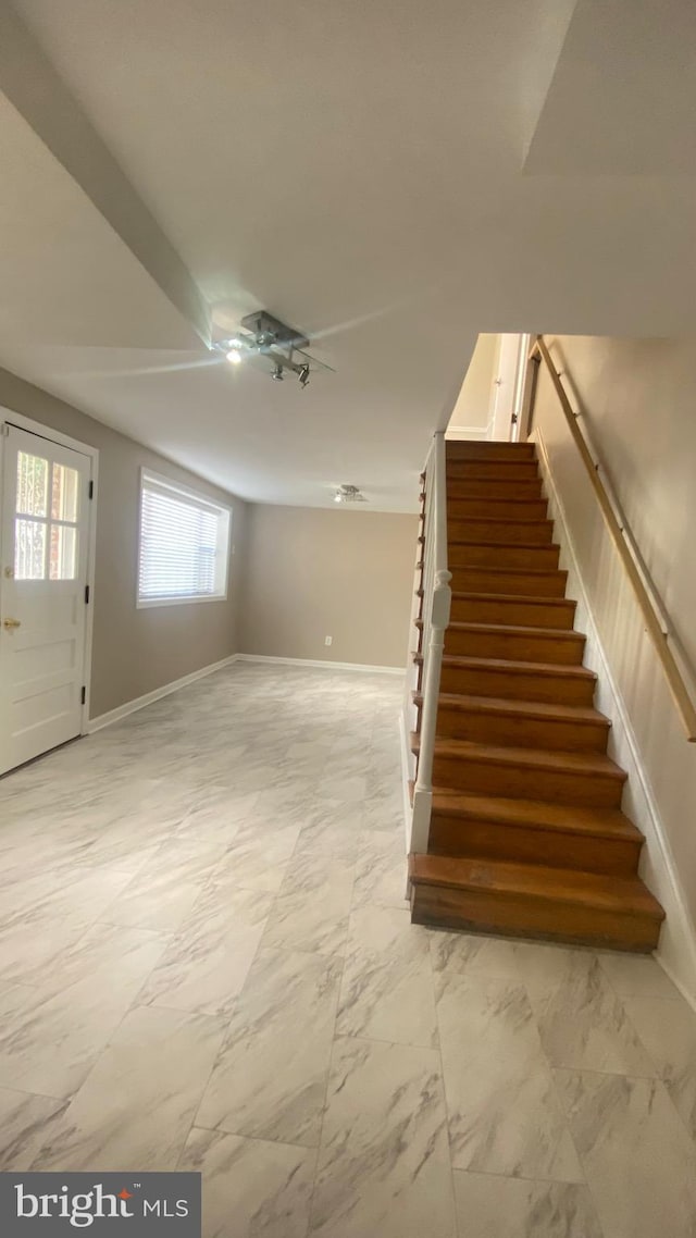 interior space with marble finish floor, stairs, and baseboards