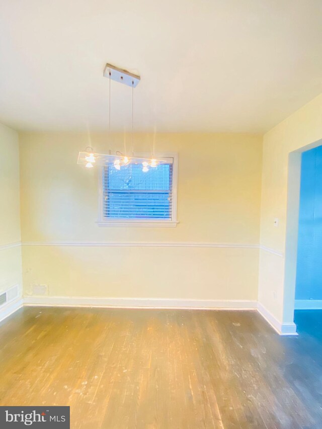 spare room with visible vents, baseboards, and wood finished floors