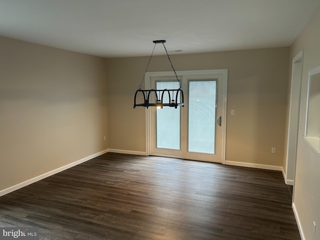 unfurnished dining area with dark hardwood / wood-style flooring and a chandelier