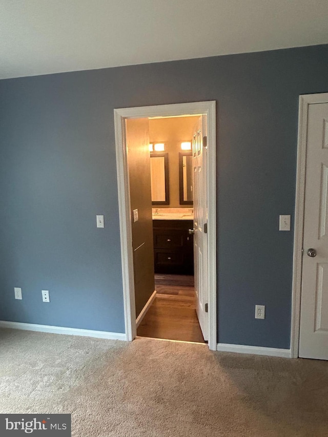 unfurnished bedroom featuring light carpet and connected bathroom