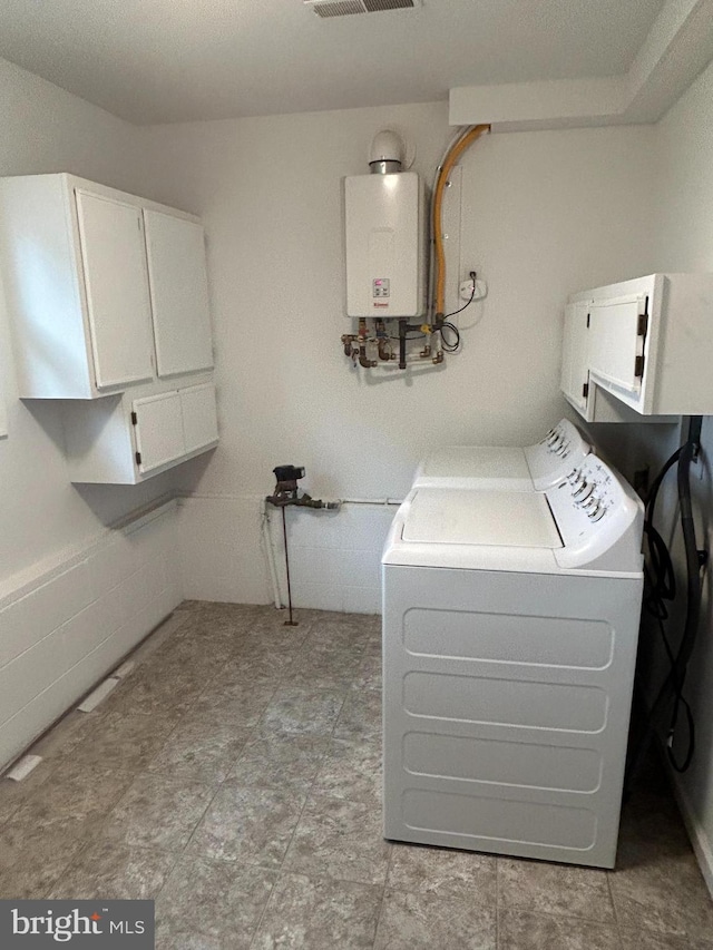 clothes washing area with tankless water heater, independent washer and dryer, and cabinets