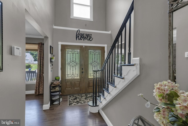 foyer featuring dark wood-type flooring, ornamental molding, french doors, and a high ceiling