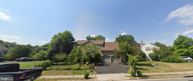 view of property hidden behind natural elements with a garage and a front lawn