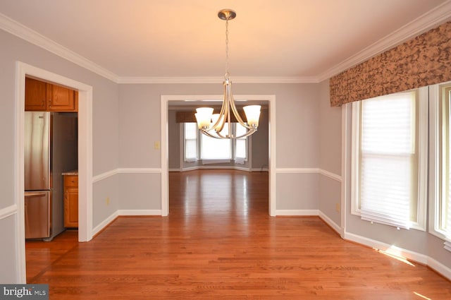 unfurnished dining area featuring a notable chandelier, ornamental molding, light wood-type flooring, and plenty of natural light