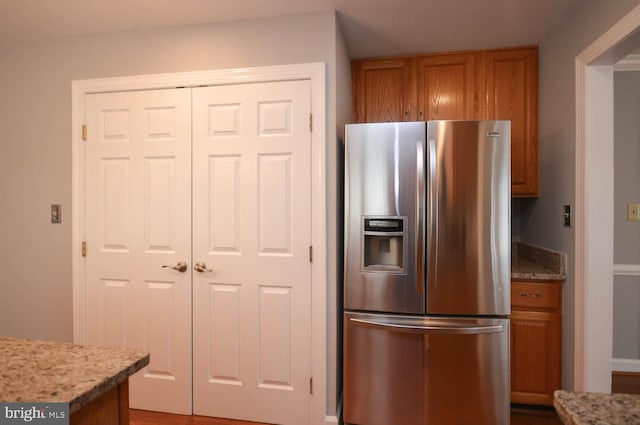 kitchen featuring stainless steel refrigerator with ice dispenser and light stone counters