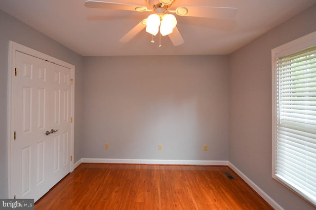 unfurnished bedroom featuring ceiling fan, wood-type flooring, and a closet