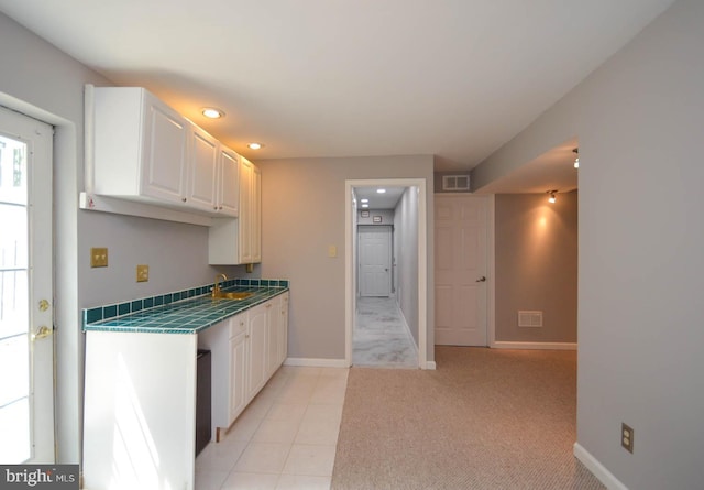 kitchen with light carpet, white cabinetry, and sink