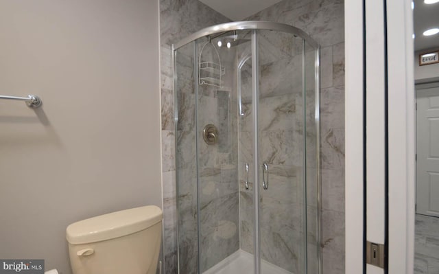 bathroom with a shower with shower door and toilet