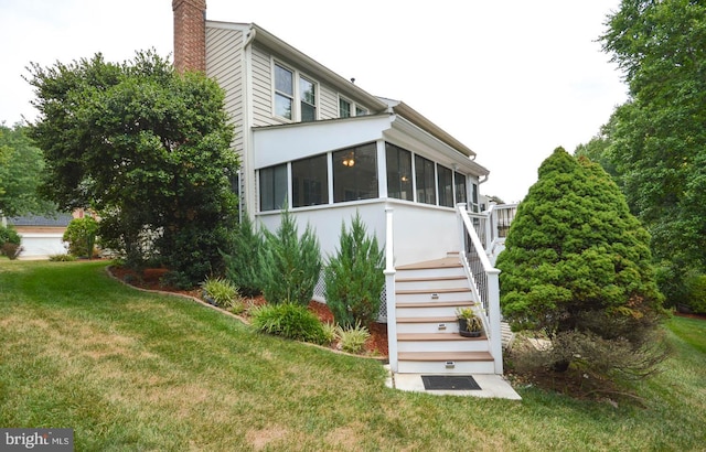 rear view of property with a sunroom and a yard