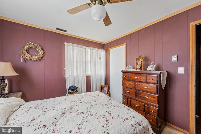 bedroom with ceiling fan and wood walls