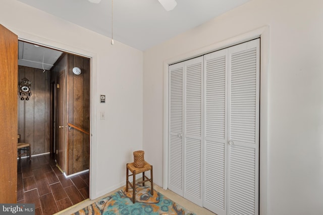 unfurnished bedroom with wooden walls, a closet, and ceiling fan