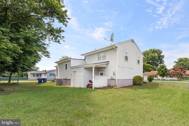 rear view of property featuring cooling unit and a lawn