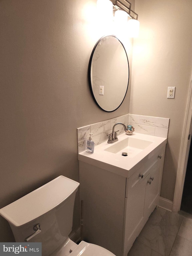 bathroom with vanity, toilet, and backsplash