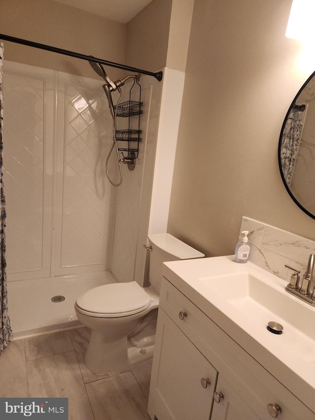 bathroom featuring a shower, toilet, and vanity