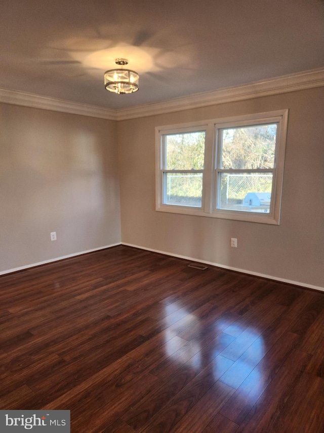 empty room featuring dark wood-style floors, plenty of natural light, baseboards, and ornamental molding