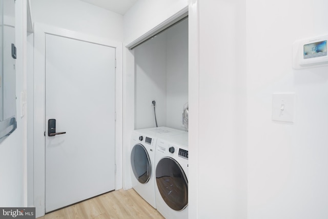 laundry area featuring washer and dryer and light hardwood / wood-style floors