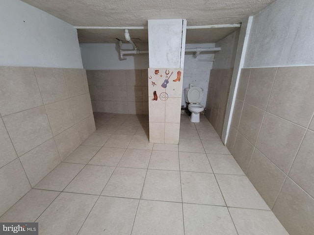 bathroom featuring tile patterned floors, tile walls, and toilet