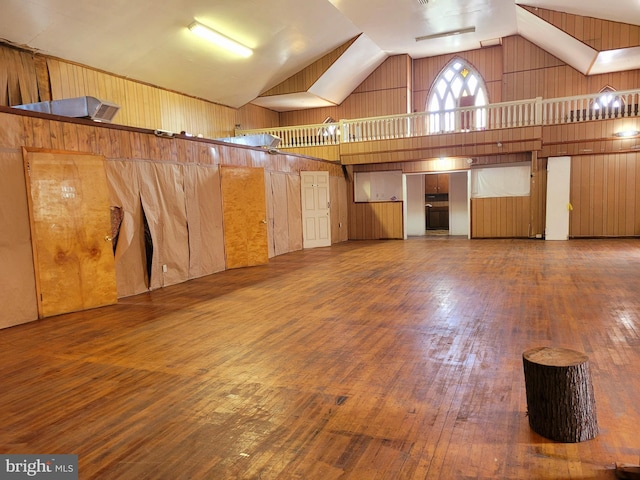 interior space with wood walls, high vaulted ceiling, and hardwood / wood-style flooring