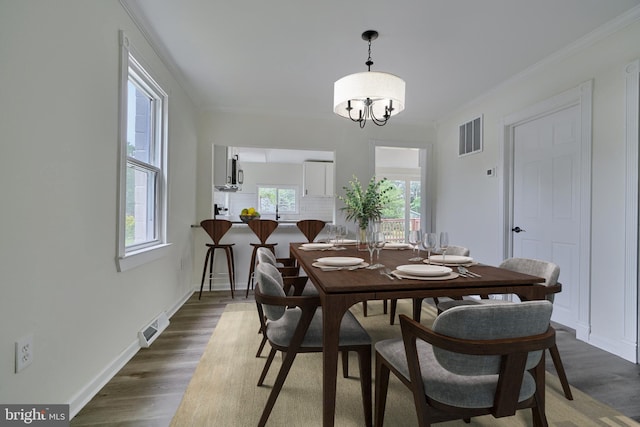 dining area with crown molding, dark wood-type flooring, and a notable chandelier