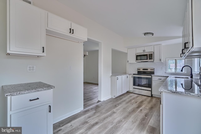 kitchen featuring white cabinetry, sink, light stone countertops, and appliances with stainless steel finishes