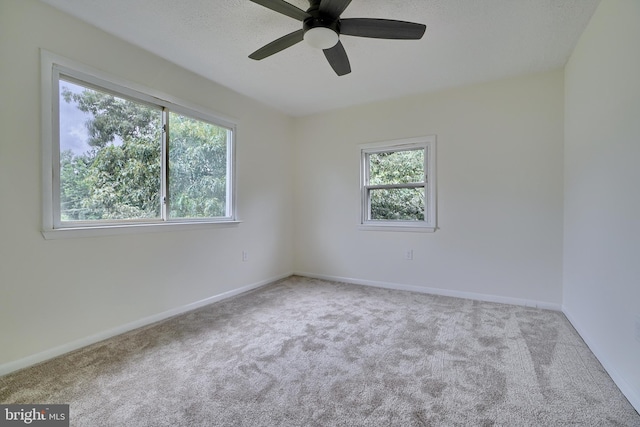 empty room featuring light carpet, a wealth of natural light, and ceiling fan