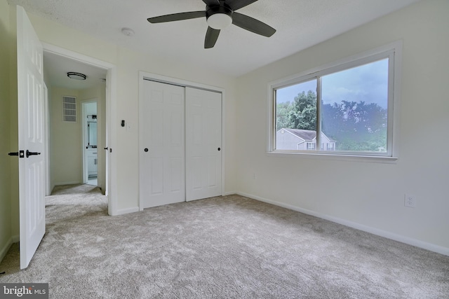 unfurnished bedroom featuring light colored carpet, a closet, and ceiling fan