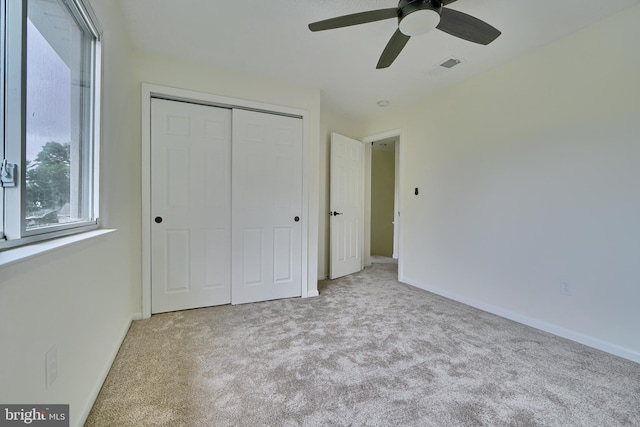 unfurnished bedroom with light colored carpet, ceiling fan, and a closet