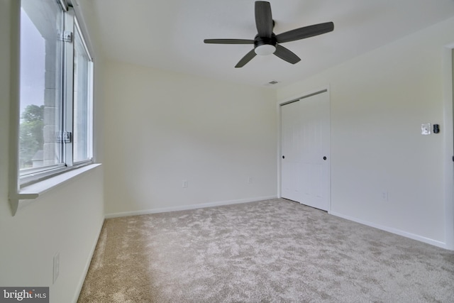 spare room featuring light carpet and ceiling fan