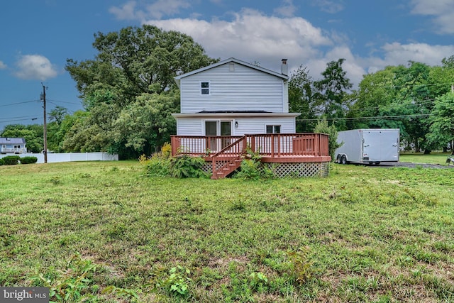 rear view of house featuring a wooden deck and a yard