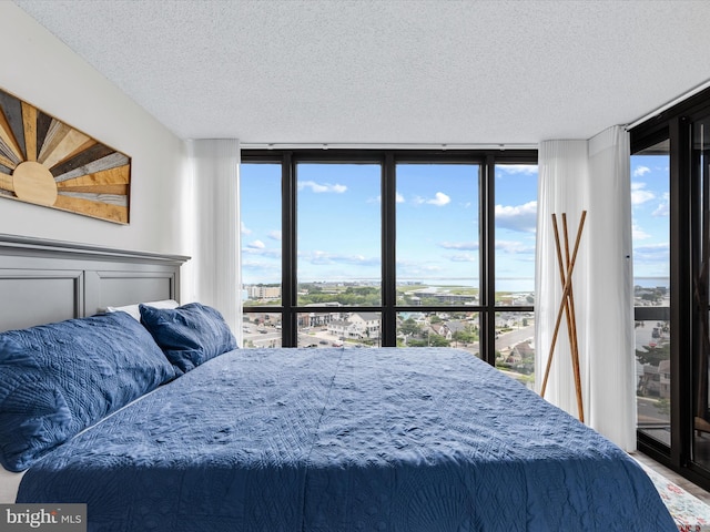 bedroom featuring a wall of windows and a textured ceiling