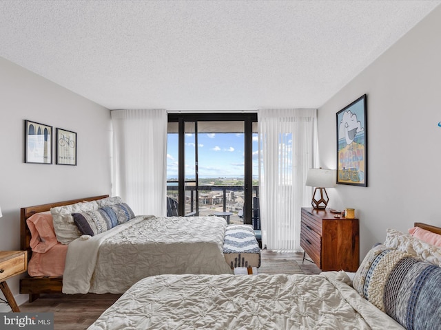 bedroom with floor to ceiling windows, access to exterior, a textured ceiling, and hardwood / wood-style flooring