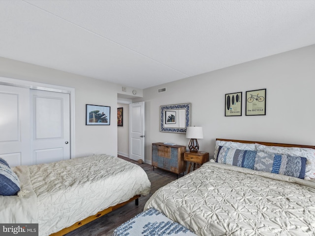 bedroom with dark hardwood / wood-style flooring and a closet