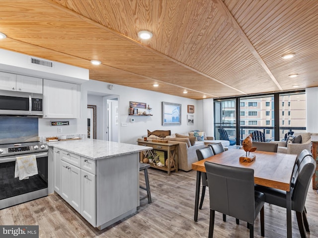 kitchen with white cabinets, appliances with stainless steel finishes, floor to ceiling windows, and wooden ceiling