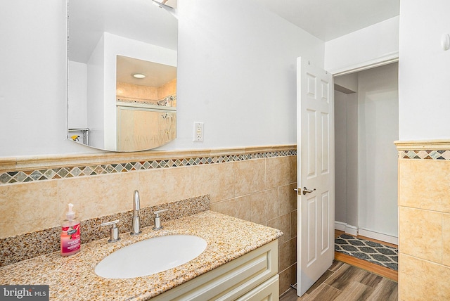 bathroom with hardwood / wood-style floors, vanity, and tile walls