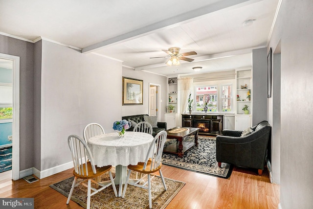 dining area featuring beam ceiling, ceiling fan, built in features, and light wood-type flooring