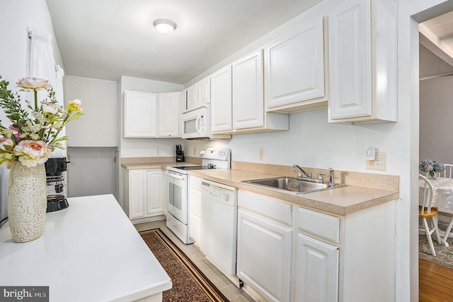 kitchen featuring sink, white cabinets, white appliances, and hardwood / wood-style flooring