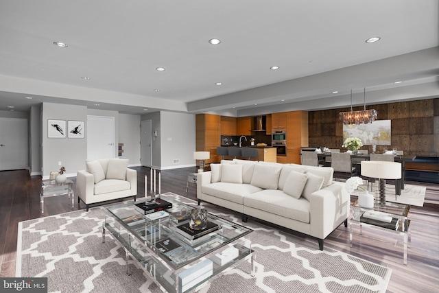 living room with sink, dark wood-type flooring, and an inviting chandelier