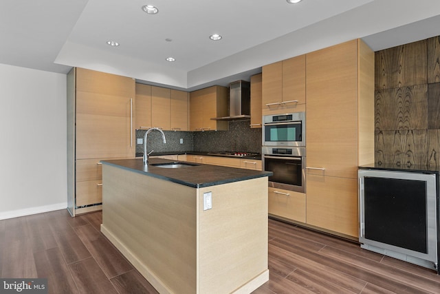 kitchen featuring sink, wall chimney exhaust hood, an island with sink, stainless steel double oven, and gas cooktop