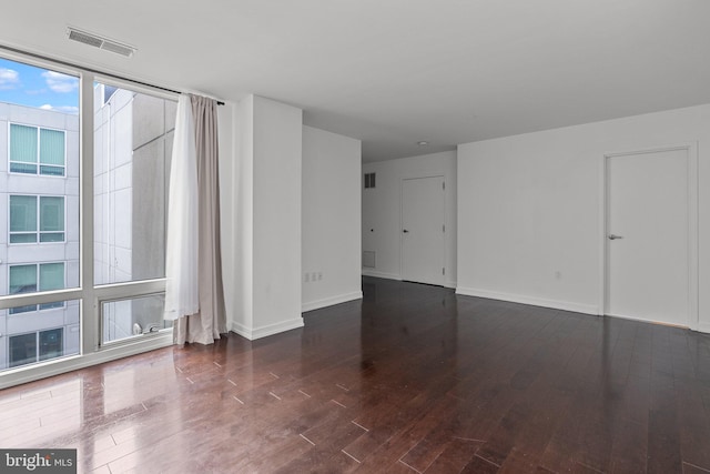 unfurnished room with dark hardwood / wood-style floors and a wall of windows