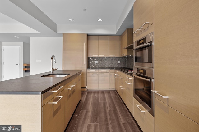 kitchen with sink, stainless steel appliances, dark hardwood / wood-style flooring, an island with sink, and decorative backsplash