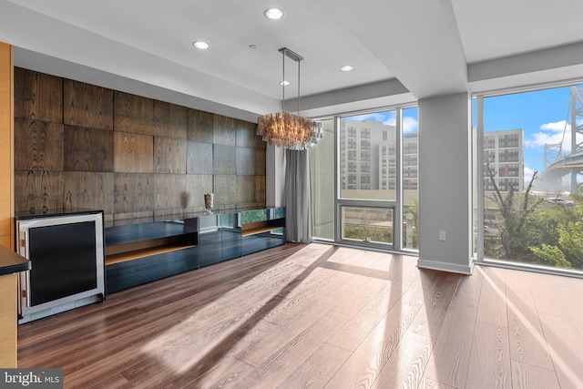 interior space featuring a healthy amount of sunlight, wood-type flooring, beverage cooler, and a chandelier