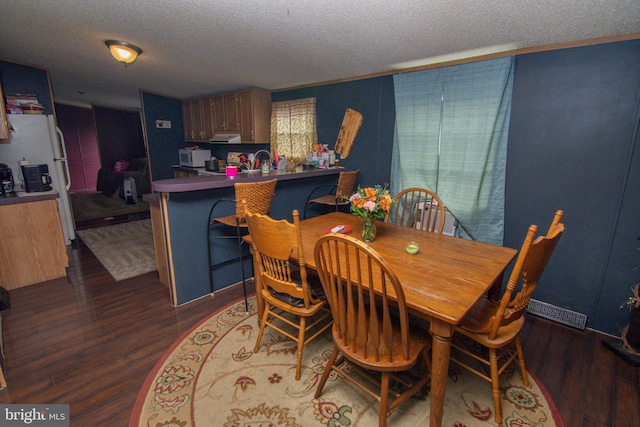 dining area with a textured ceiling and dark hardwood / wood-style floors