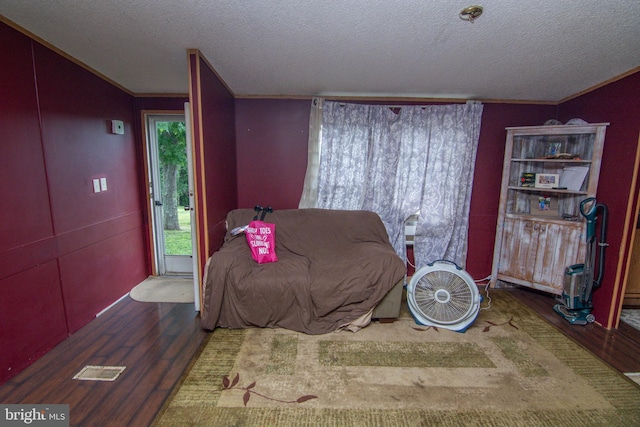 bedroom with crown molding, wood-type flooring, and a textured ceiling