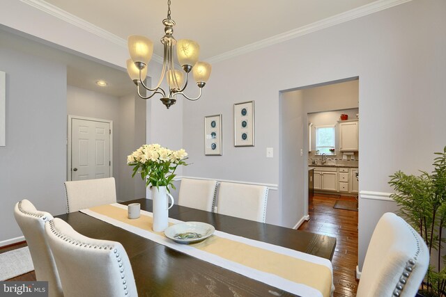 dining area with an inviting chandelier, sink, dark hardwood / wood-style floors, and crown molding