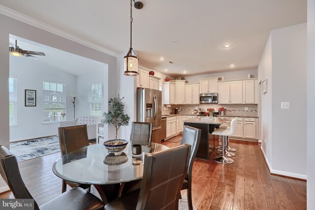 dining space with ceiling fan, ornamental molding, and light hardwood / wood-style floors