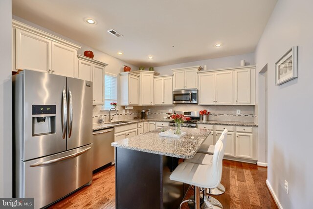 kitchen featuring light wood-type flooring, a kitchen island, sink, and stainless steel appliances